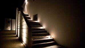 Una escalera con barandales e iluminación en los peldaños, que conduce a una puerta en la parte superior.