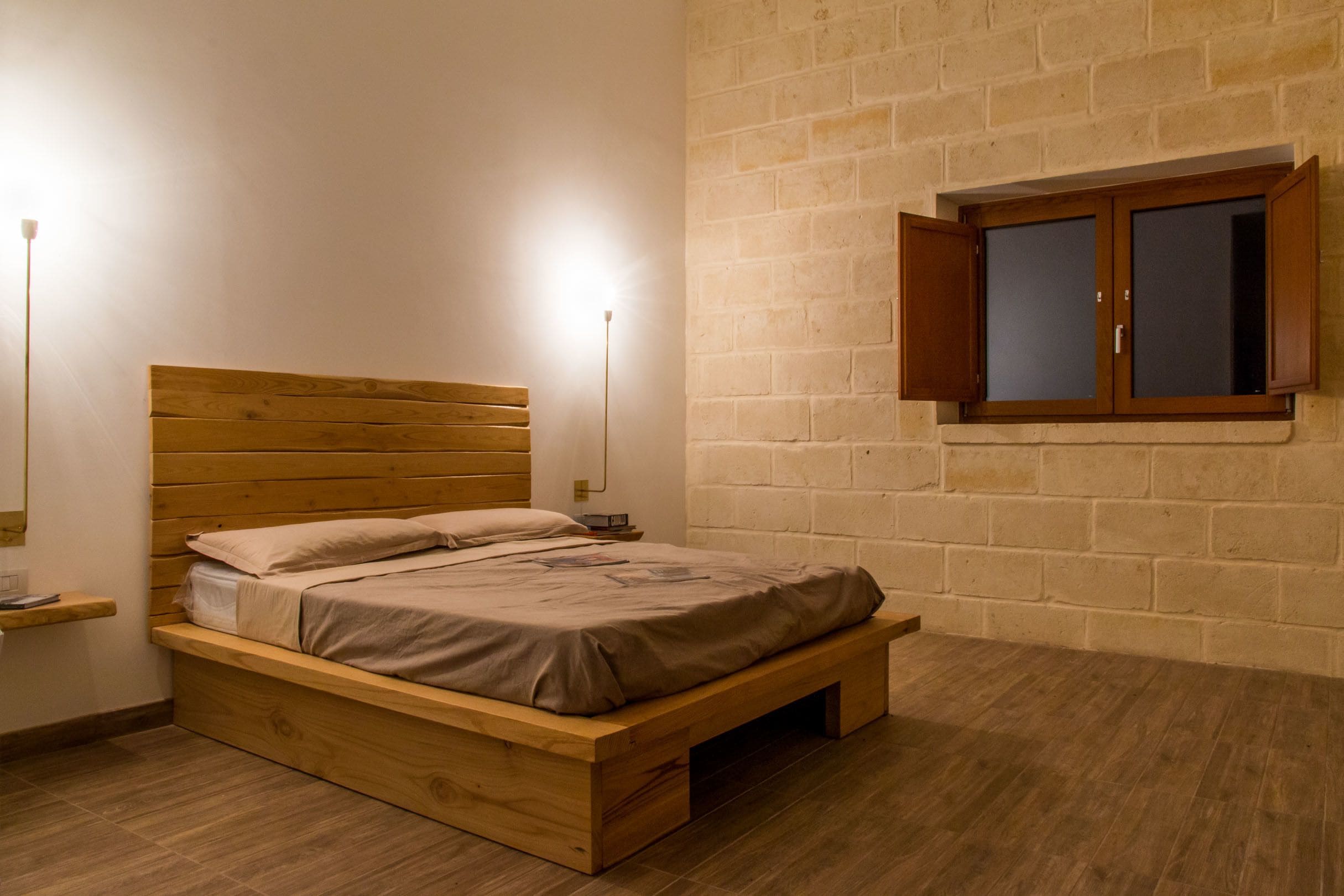 A wooden bed with a headboard, a bedside table, and a wall-mounted cabinet.