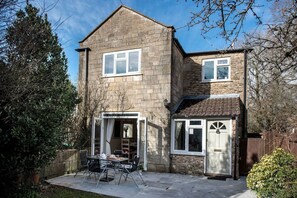 A two-story stone house with a patio area featuring a table and chairs. - Old Bakery Cosy Cottage in Bath - 3 Bedroom, Free (Bath)