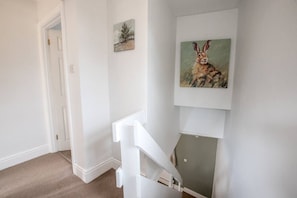 A hallway with a white staircase, a door, and a painting of a rabbit on the wall. - Old Bakery Cosy Cottage in Bath - 3 Bedroom, Free (Bath)