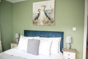 A bedroom with a bed, two bedside tables, and a wall painting of birds. - Old Bakery Cosy Cottage in Bath - 3 Bedroom, Free (Bath)