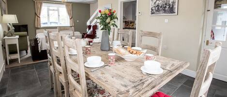 Un comedor con una mesa de madera, sillas y un florero.