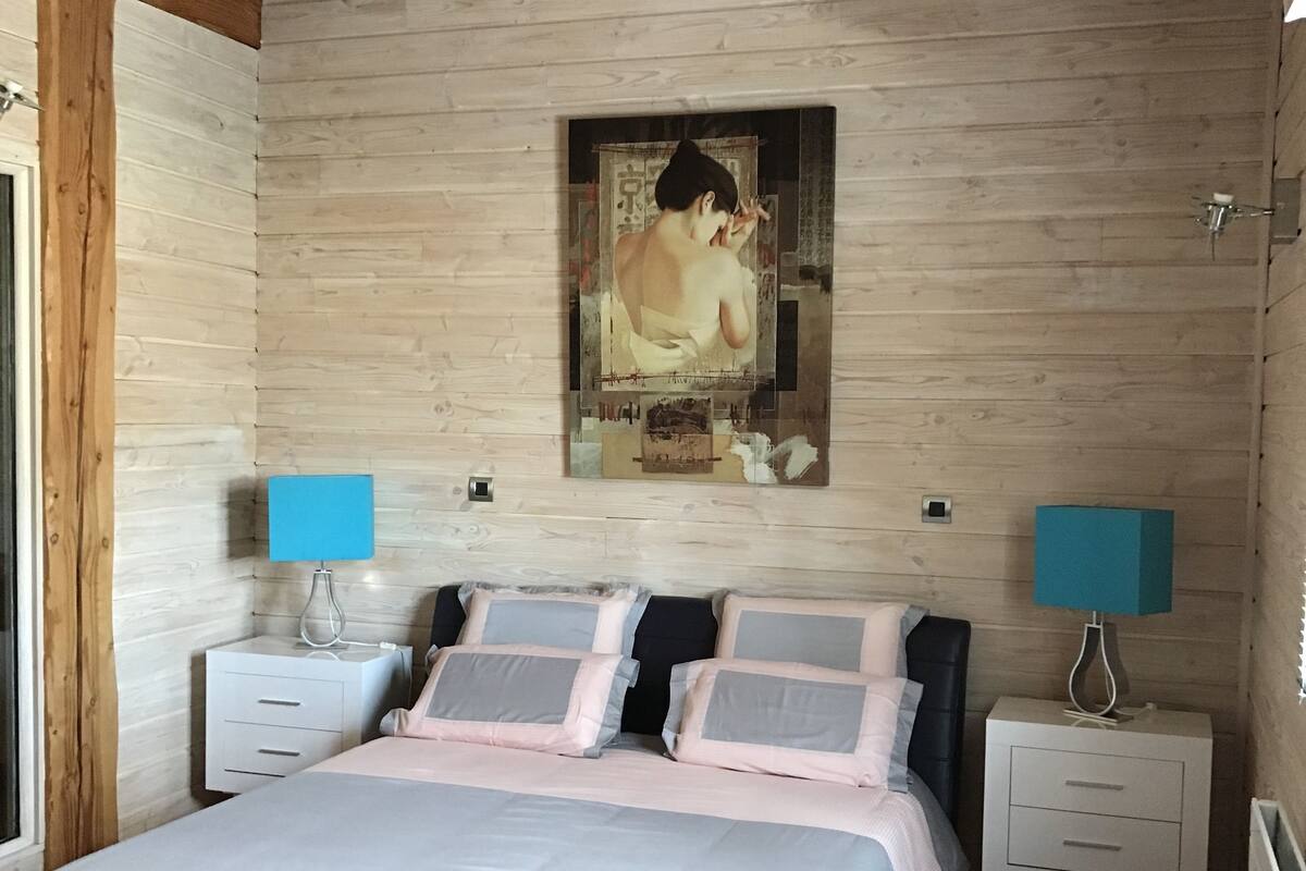 Ein Schlafzimmer mit Holzvertäfelung, einem Bett, zwei Nachttischen mit Lampen und einem großen Poster an der Wand.