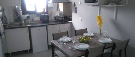 A modern kitchen with white cabinets, a microwave, and a dining table set for four.