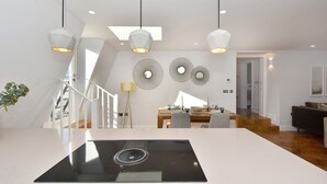A modern kitchen with a central island, pendant lighting, and a dining area with a table and chairs. - Amazing Mayfair 2 Bed £6 million AC Terrace Wi-Fi (London)