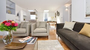 A modern living room with a sofa, two armchairs, a coffee table, and a vase with flowers. - Amazing Mayfair 2 Bed £6 million AC Terrace Wi-Fi (London)