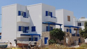 Un edificio blanco con detalles azules, que presenta una pared de piedra y un bote al frente.