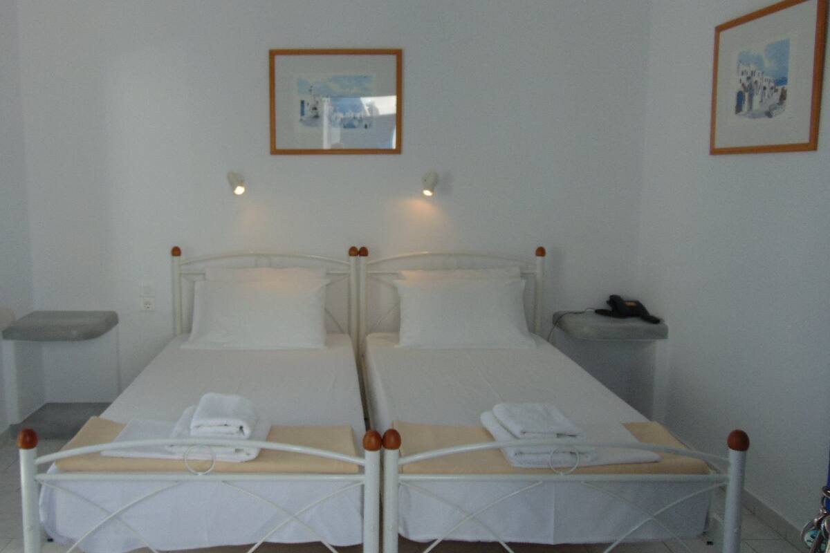 A twin room with two beds, a bedside table, a mirror, and a framed picture on the wall.