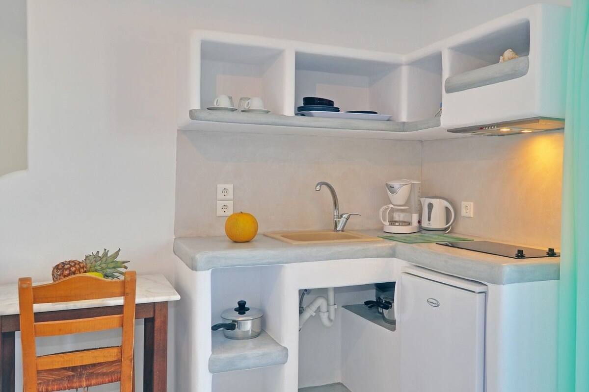 A compact kitchen with a sink, coffee maker, and a small refrigerator.