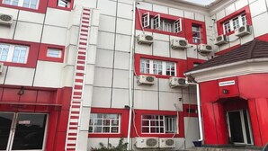 A multi-story building with a red and white color scheme, featuring multiple air conditioning units, a reception area, and a staircase. - Jim-Eddy Suites (Enugu)