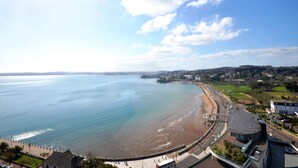 A coastal view with a beach, promenade, and buildings along the shore.