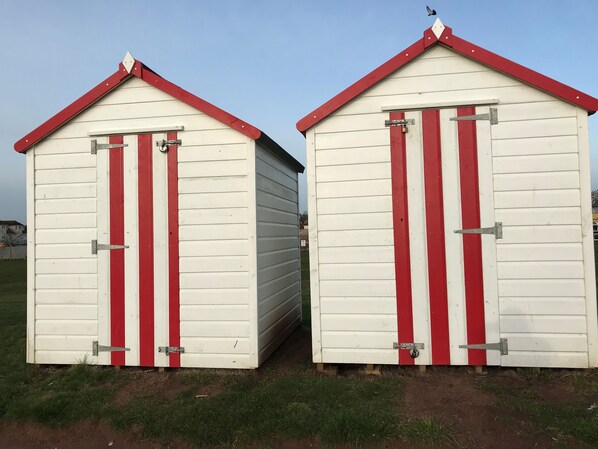 Two small, white buildings with red trim and doors, featuring metal latches and a simple, functional design. - Smart one bed apartment with sea views (Torquay)