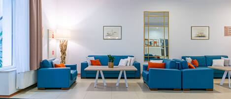 A modern living room with blue sofas, a wooden coffee table, and a large mirror.