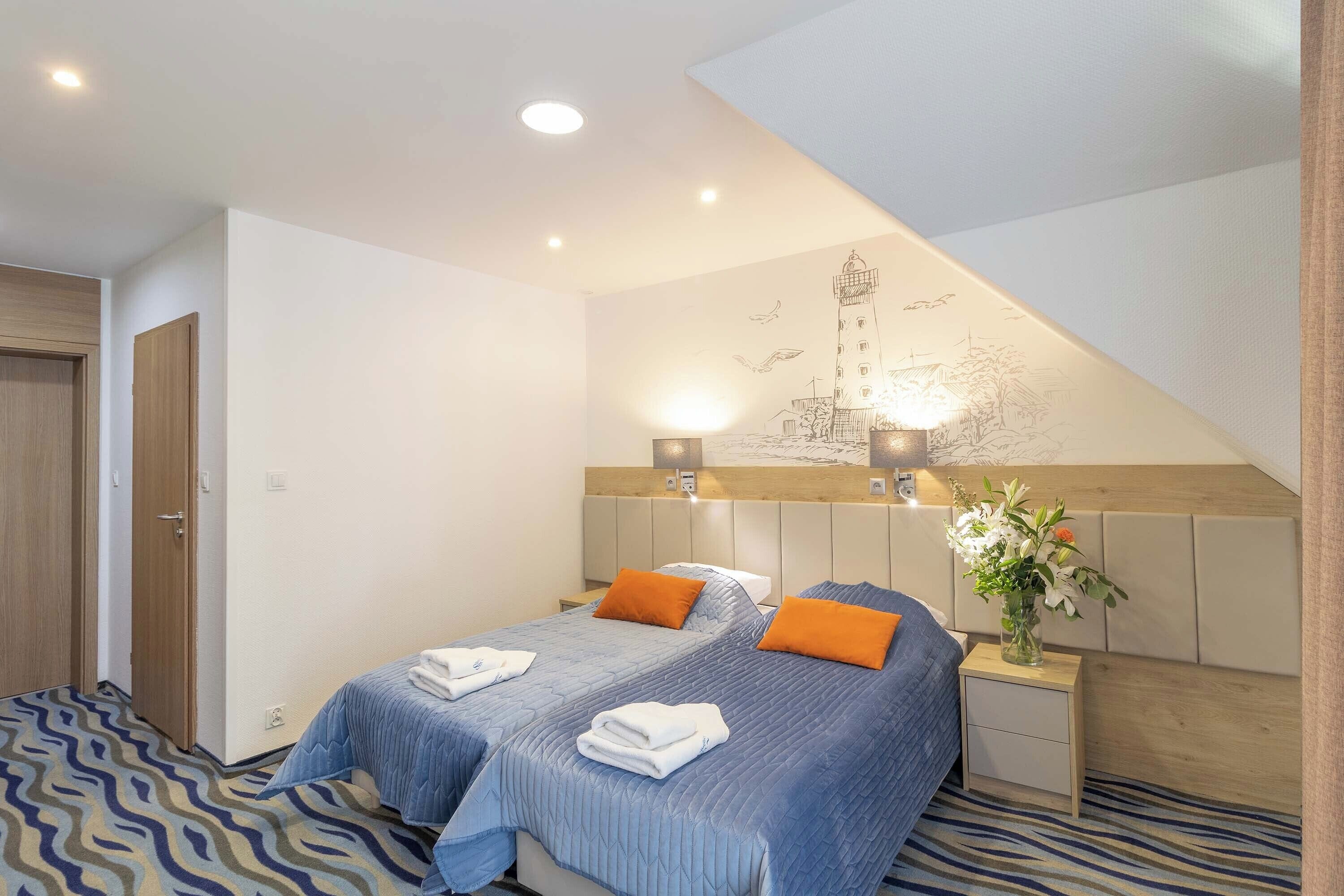 A hotel room with two beds, a wooden headboard, a nightstand with a vase of flowers, and a wall mural.