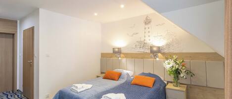 A hotel room with two beds, a wooden headboard, a nightstand with a vase of flowers, and a wall mural.