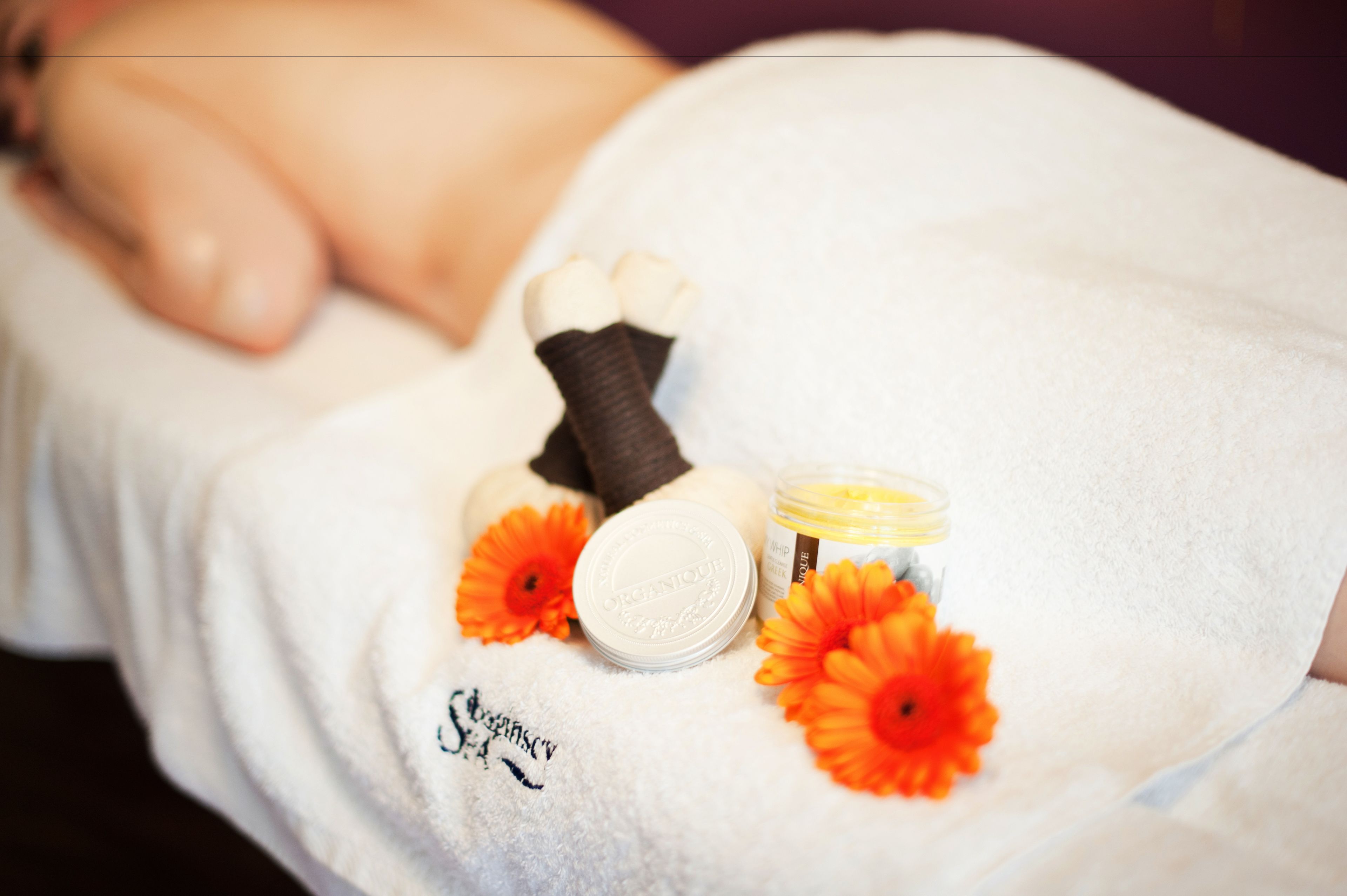 A spa setting with a white towel, a foot bath, and orange flowers.