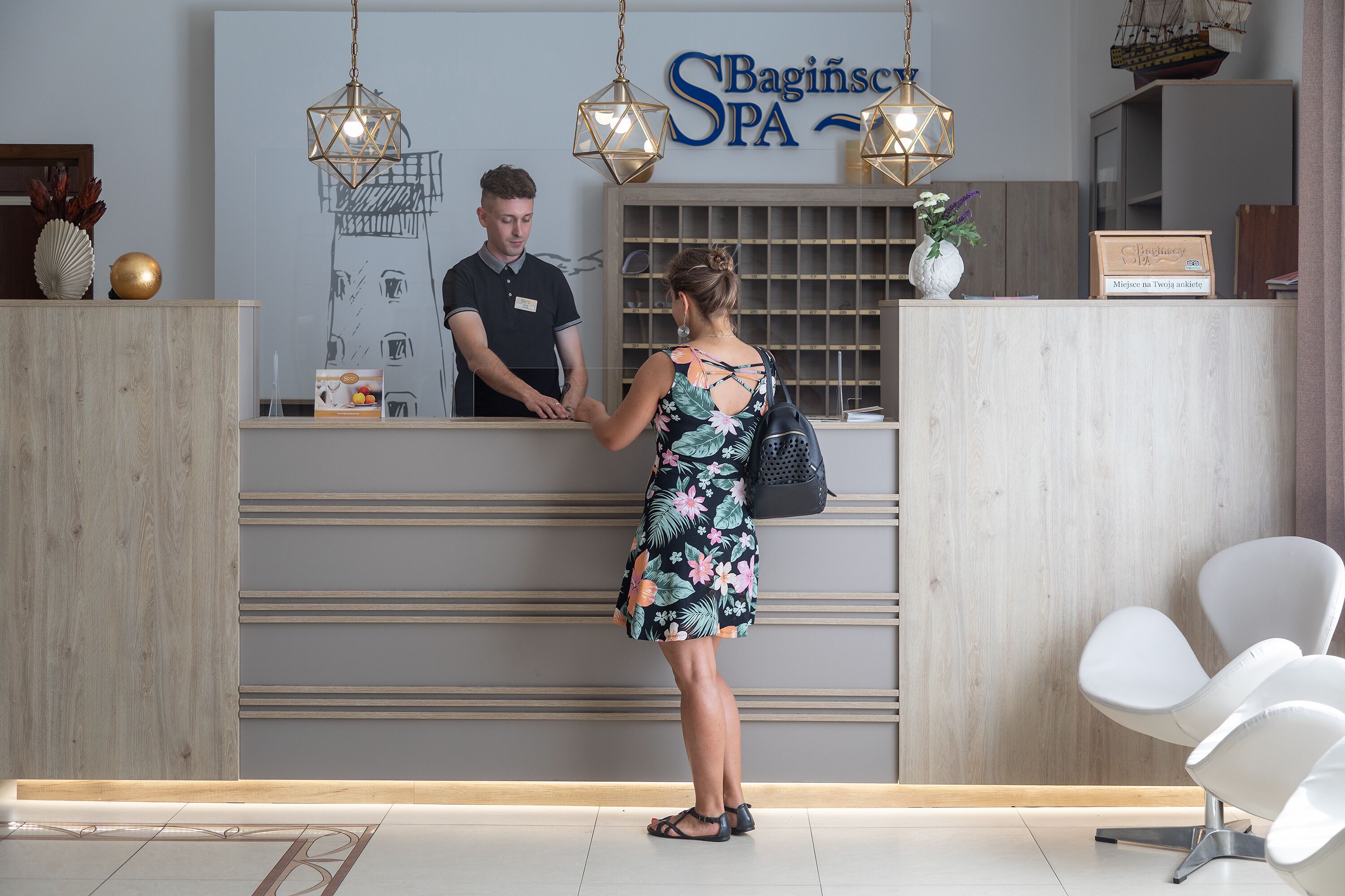 Una recepción con un cartel que dice 'Bagiński SPA' y un hombre detrás.
