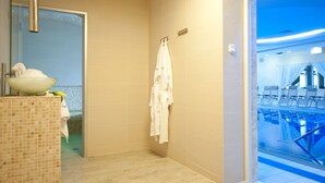 Une salle de bain avec une douche, un lavabo et un porte-serviettes.