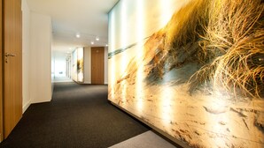 Un couloir avec un mur à texture et une porte sur laquelle est inscrit le mot « SORTIE ».