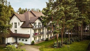 Un immeuble à plusieurs étages, doté d’une façade blanche, de nombreux balcons et entouré d’une zone verdoyante avec des arbres.