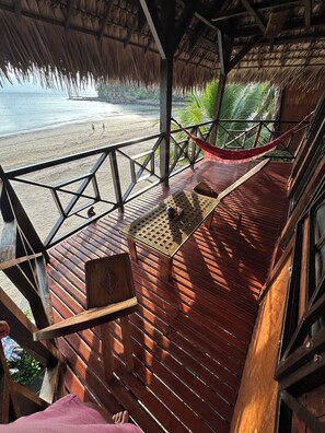 A wooden deck with a hammock, a table, and a view of the beach. - Waterfront villa with live-in staff! (NOSY BE)