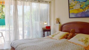 A bedroom with a bed, a teddy bear, a lamp, and a painting on the wall.