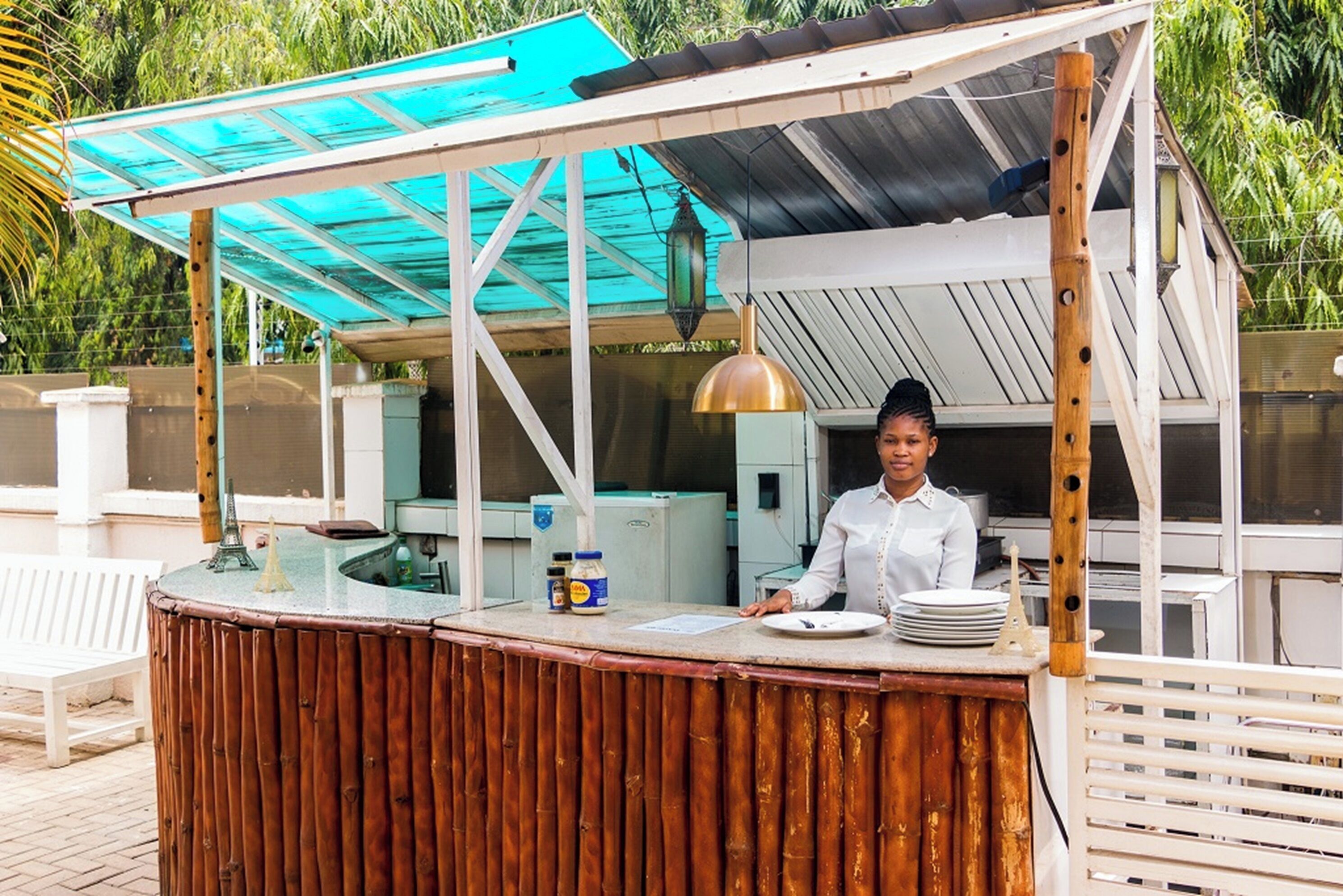 A food kiosk with a wooden counter, a blue awning, and a person serving.
