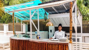 Un stand de restauration avec un comptoir en bois, un auvent bleu et une personne qui sert les clients.