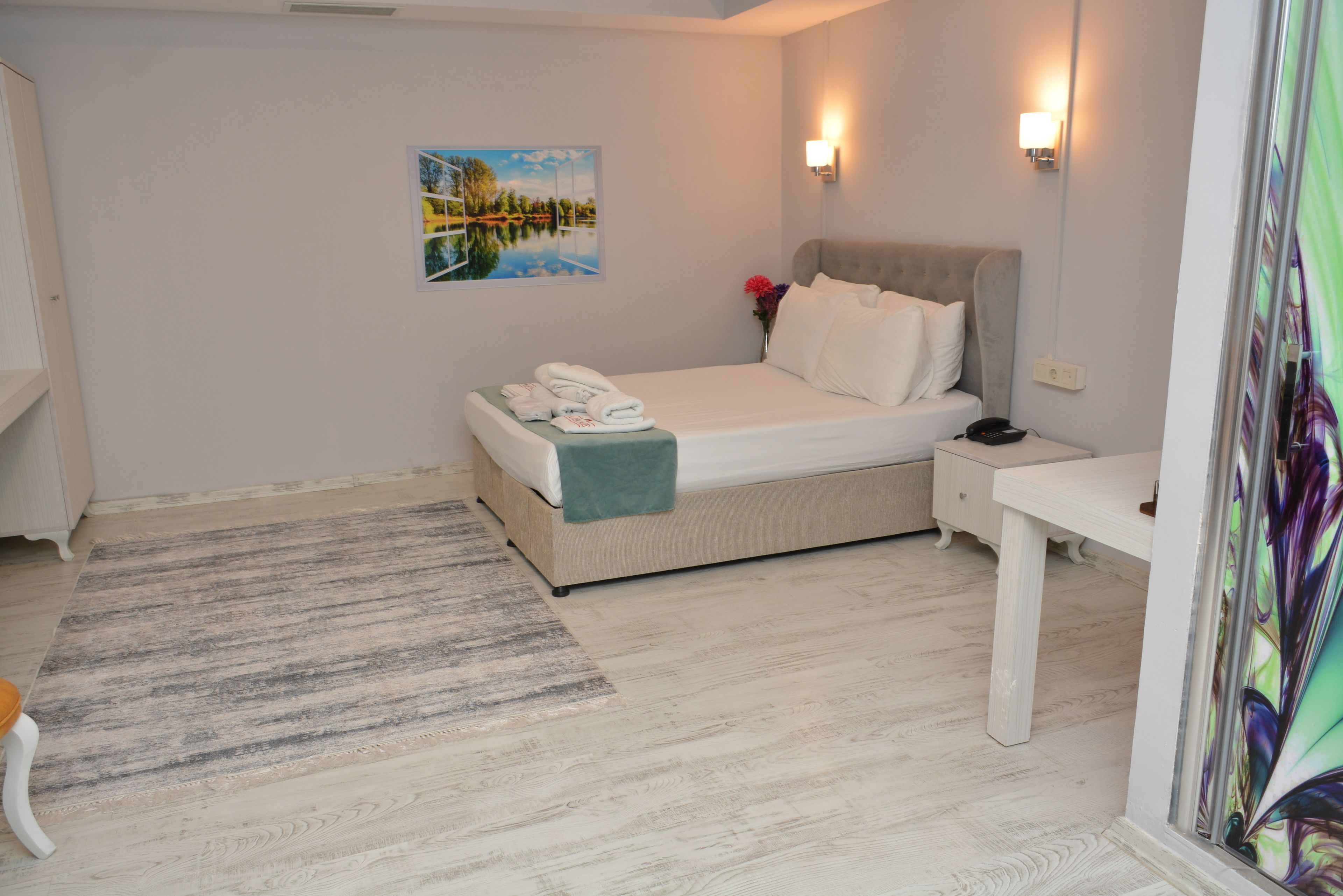 A bedroom with a bed, bedside table, and a painting on the wall.