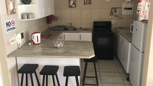 Une cuisine de taille réduite avec un îlot central, des meubles blancs, une cuisinière et un réfrigérateur.
