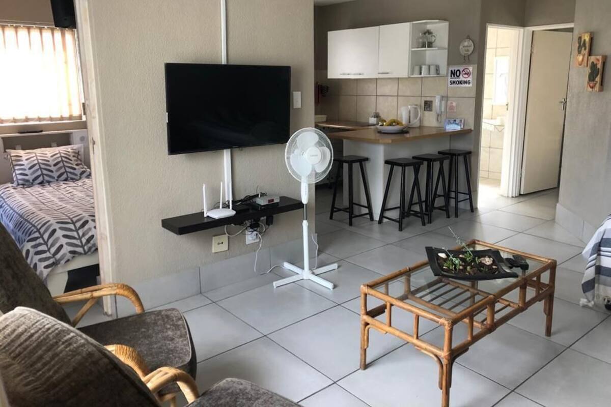 Ein modernes Wohnzimmer mit Fernseher, einem Standventilator und einem Couchtisch.