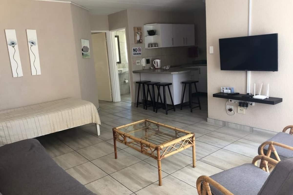 Ein Wohnzimmer mit einer Couch, einem Glastisch und einem an der Wand befestigten Fernseher.