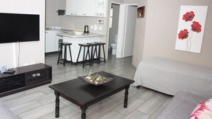 Un salon moderne avec une table basse en bois foncé, un canapé gris et un téléviseur à écran plat posé sur un meuble.