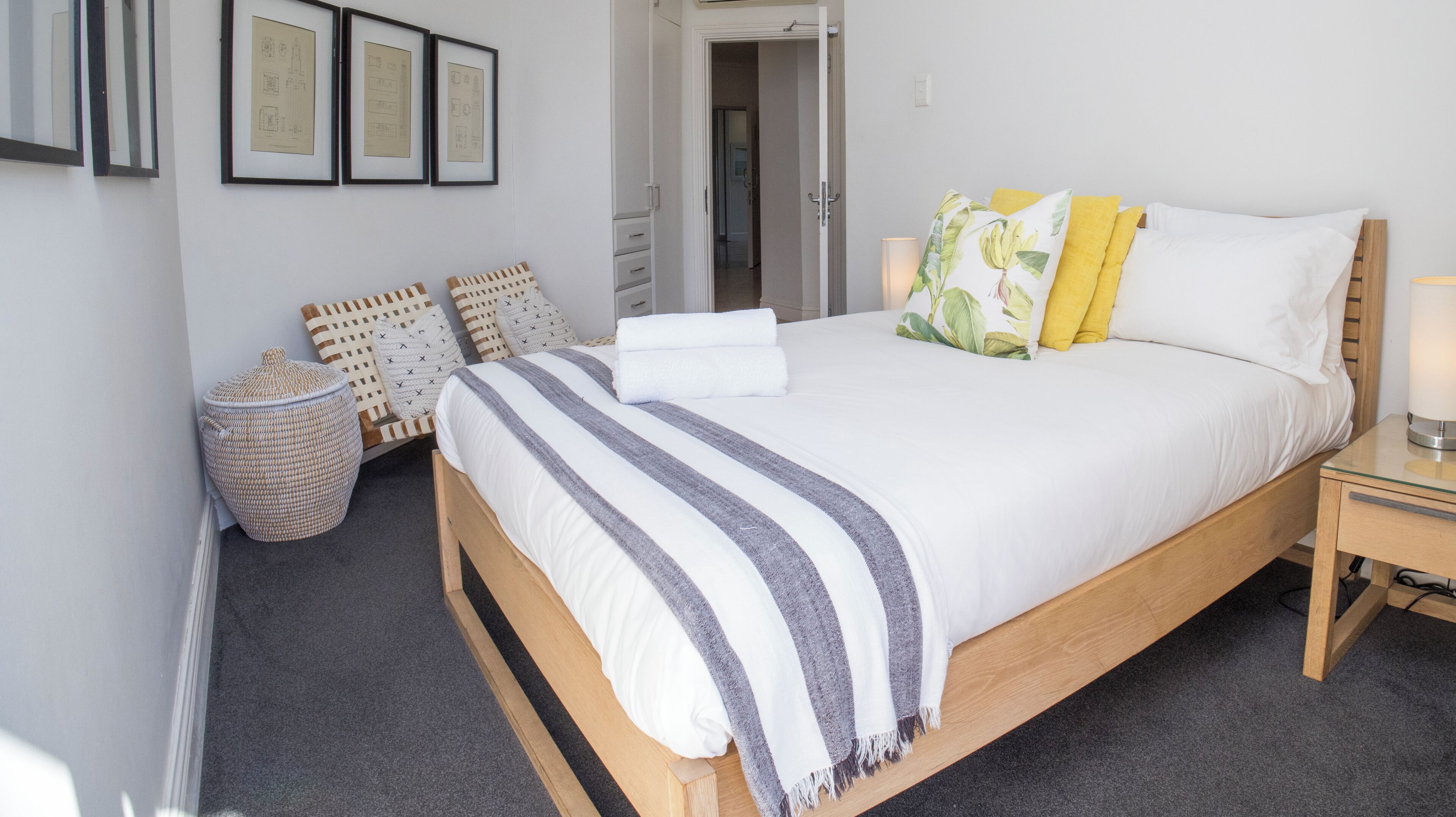 A neatly made bed with a striped blanket, a bedside lamp, and a nightstand.
