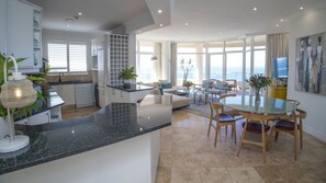 Een moderne keuken met een eethoek, grote ramen en uitzicht op zee.
