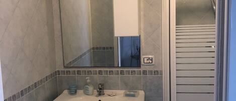 A bathroom with a white sink, mirror, and shower.