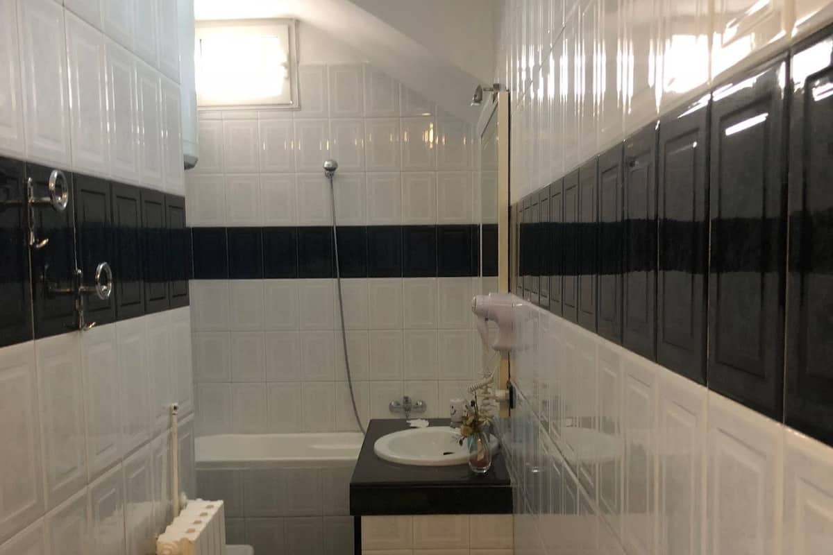 A compact bathroom with white and black tiles, a white sink, a toilet, and a shower.