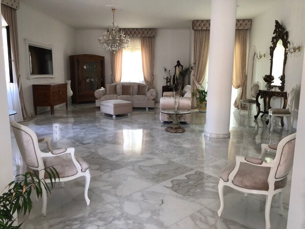 A spacious living room with a marble floor, a large chandelier, and a sofa set. - Villa Nicolaus (Bari)