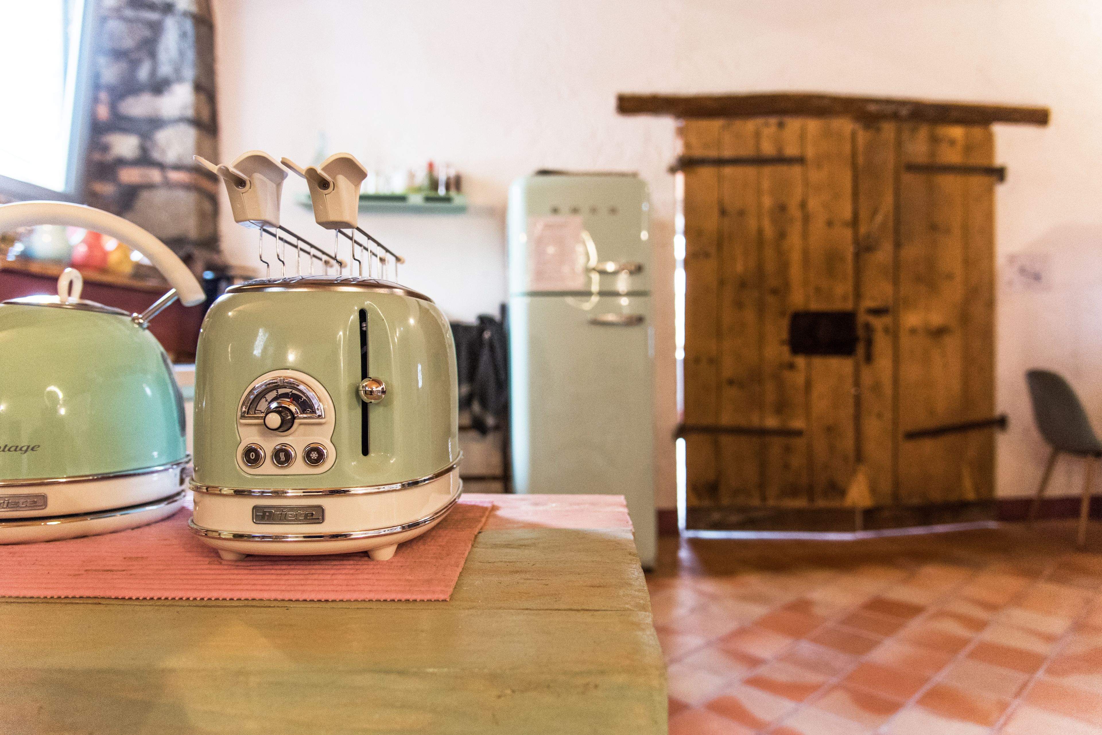 Eine Vintage-Küche mit einem grünen Toaster, einem grünen Wasserkocher und einem Holzschrank.