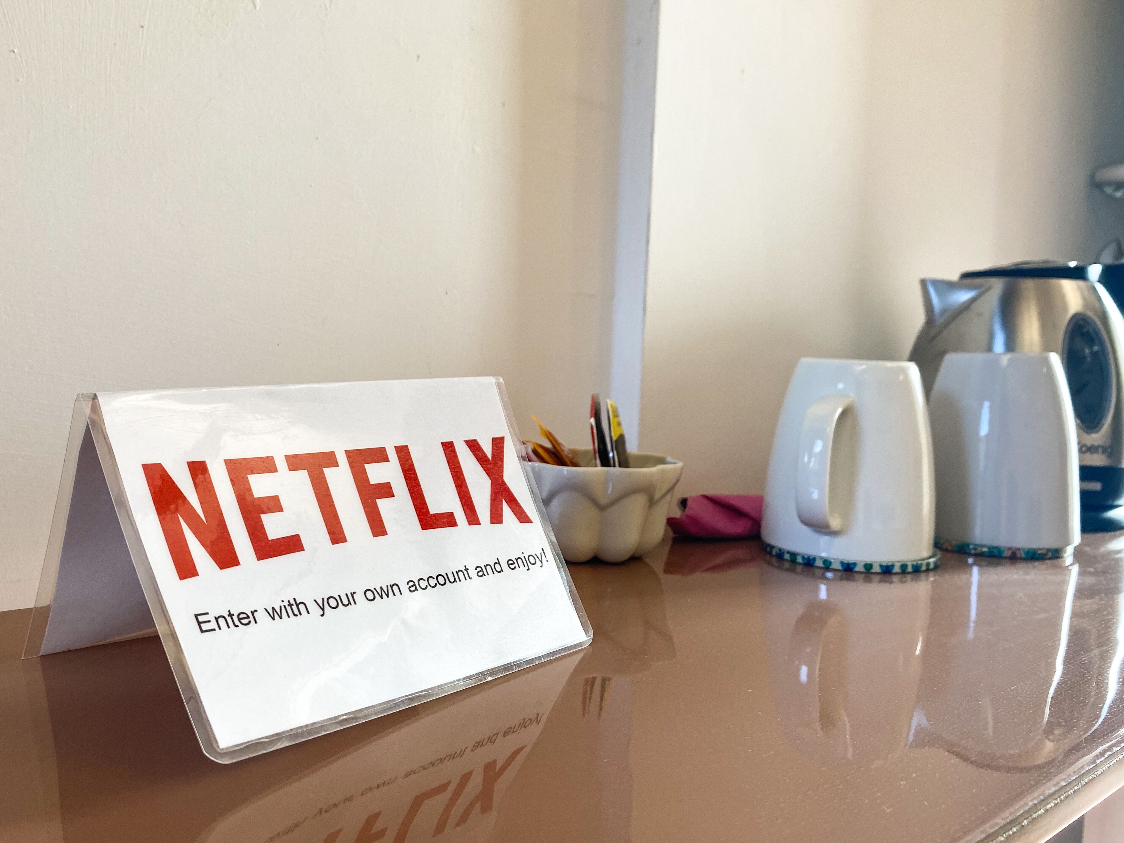 A sign on a table advertising Netflix with a message to enter with your own account and enjoy.