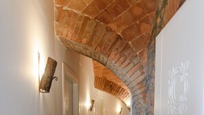 A narrow hallway with a brick archway, white walls, and a wooden floor. - Casale 1541 (Bolsena)