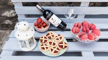 Une table avec une bouteille de vin, un verre, un bol de fraises et une assiette de biscuits.