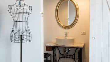 Un baño con tocador, espejo redondo e iluminación colgante.