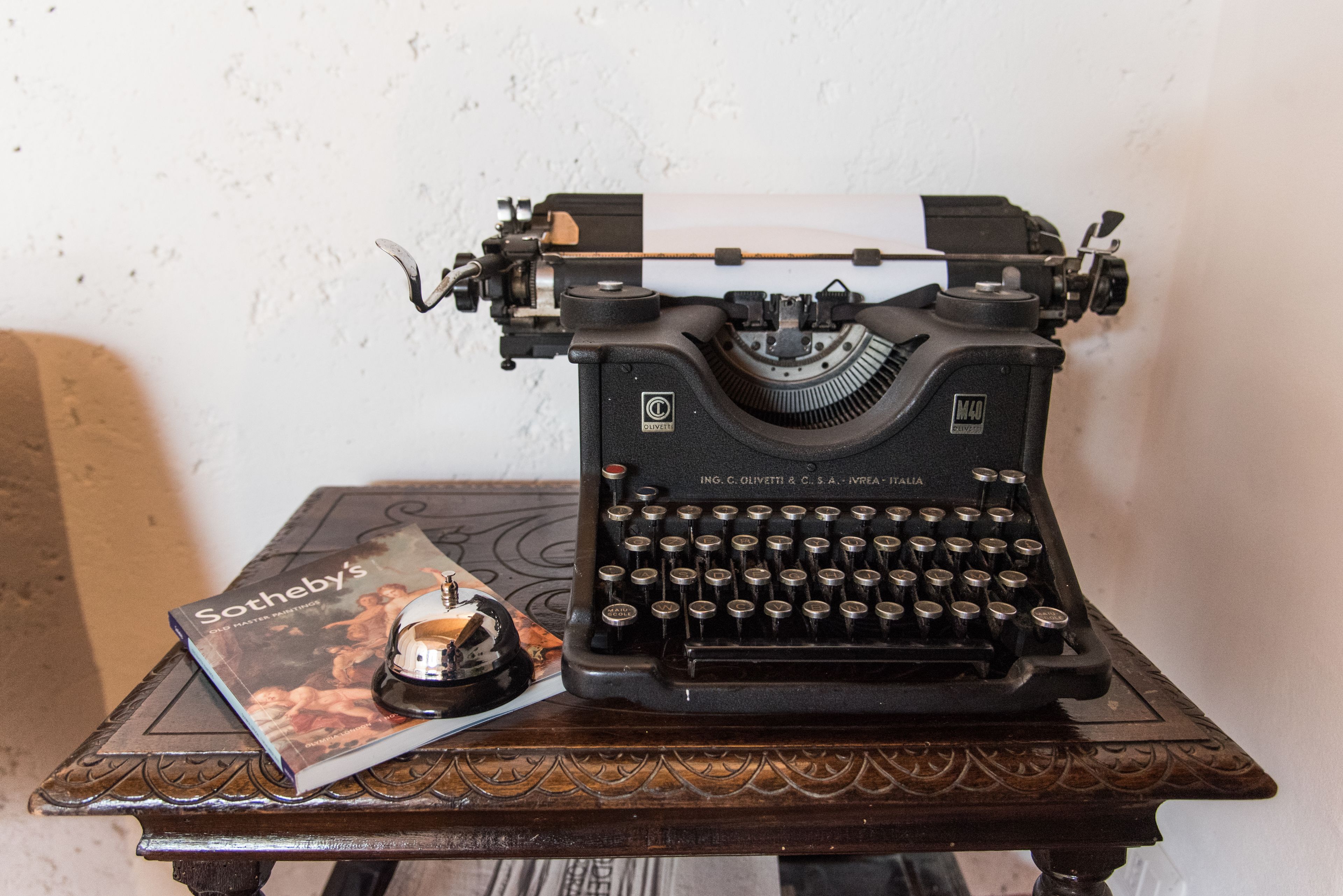 A vintage typewriter on a wooden table with a Sotheby's magazine.