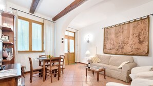 Una sala de estar acogedora con una mesa de madera, sillas, un sofá y un tapiz grande en la pared.