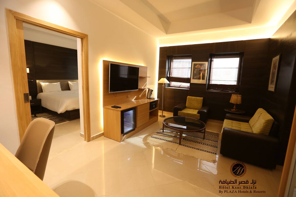 Una habitación de hotel moderna con cama, televisor, zona de estar y escritorio.