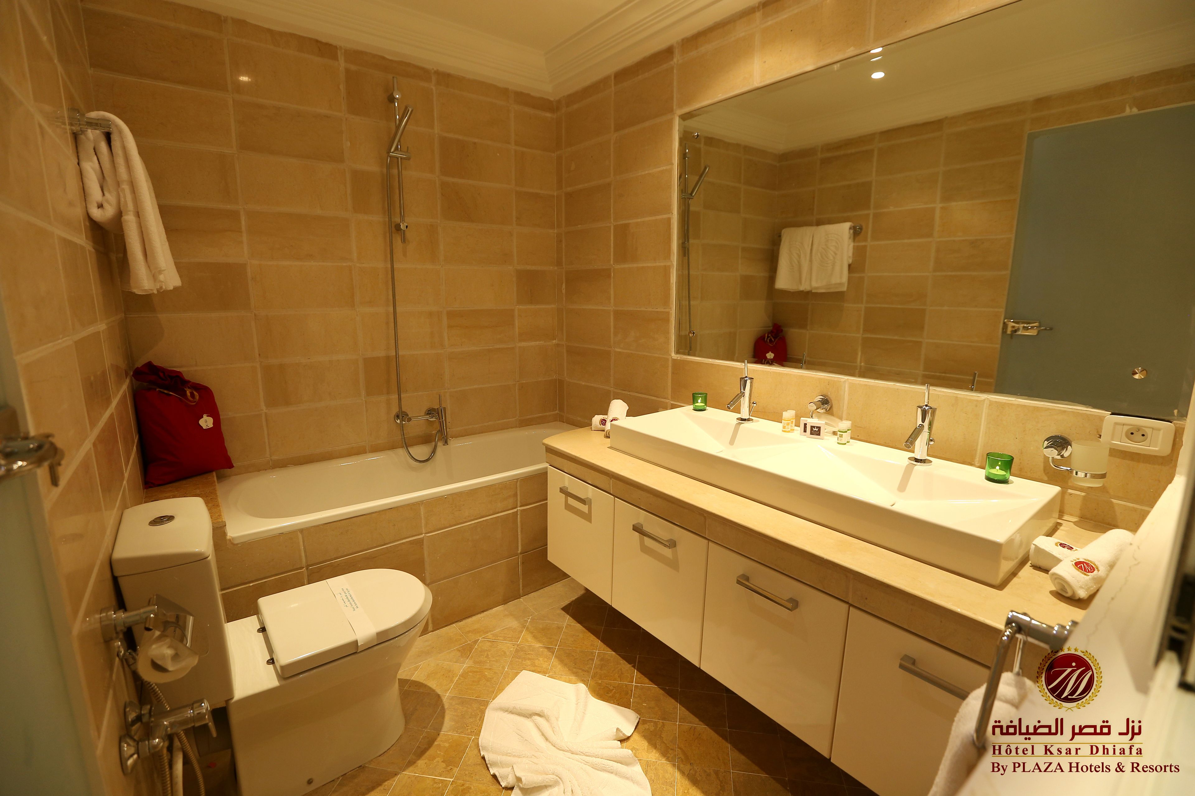 A modern bathroom with a bathtub, a toilet, and a double sink vanity.
