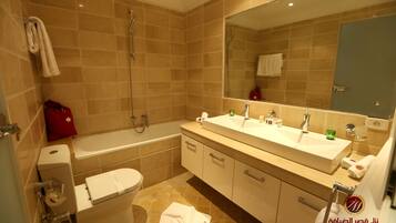A modern bathroom with a bathtub, a toilet, and a double sink vanity.