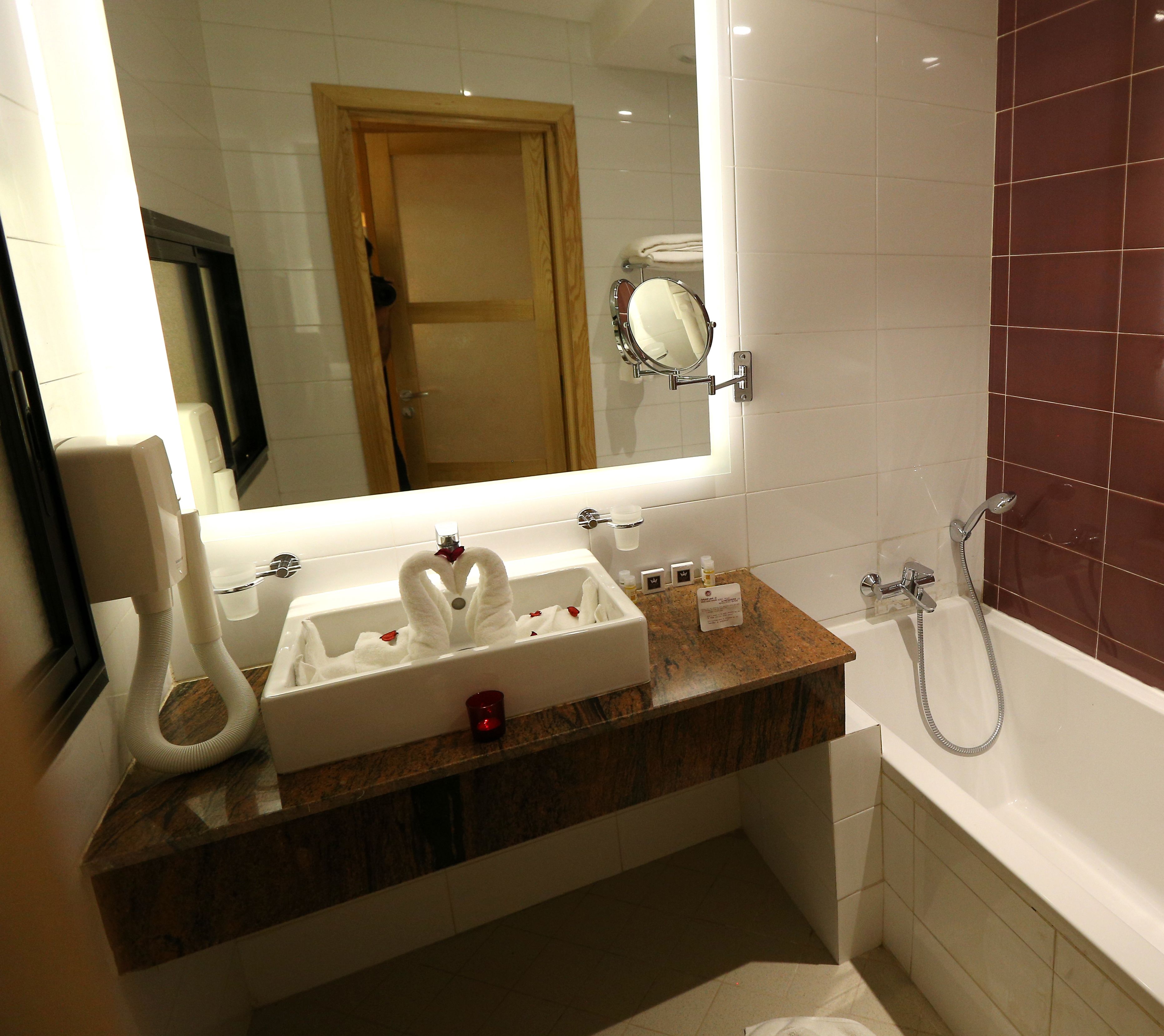 A bathroom with a sink, mirror, and shower.