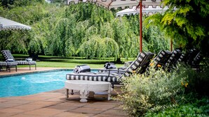 A poolside area with lounge chairs, a small table, and a covered seating area. - Hartford House (Mooirivier)